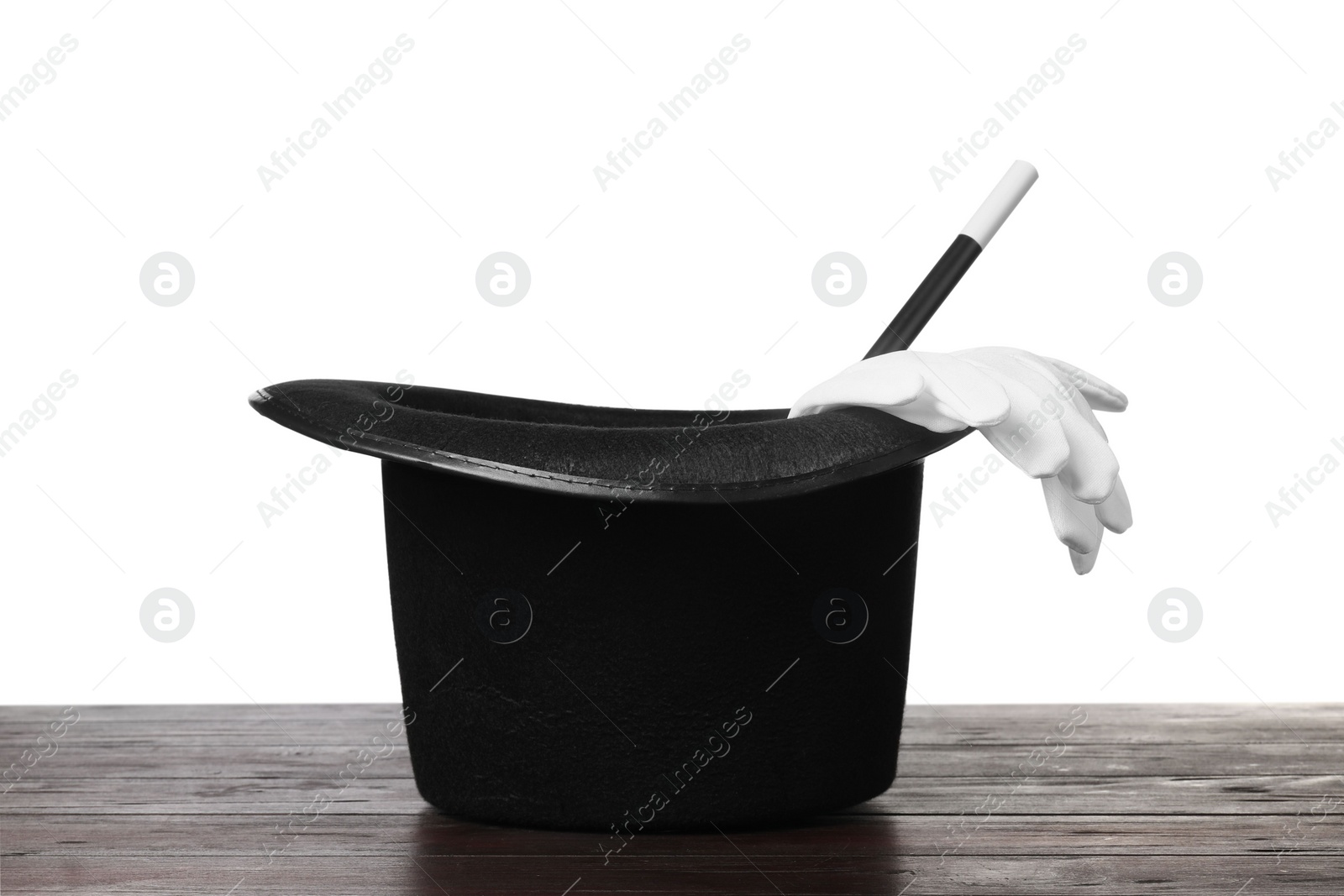 Photo of Magician's hat, gloves and wand on wooden table against white background