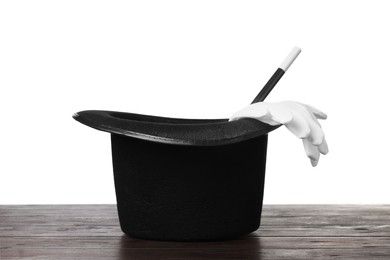 Photo of Magician's hat, gloves and wand on wooden table against white background