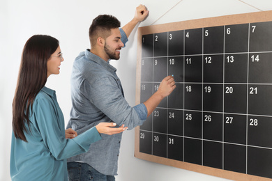Photo of Colleagues writing with chalk on board calendar