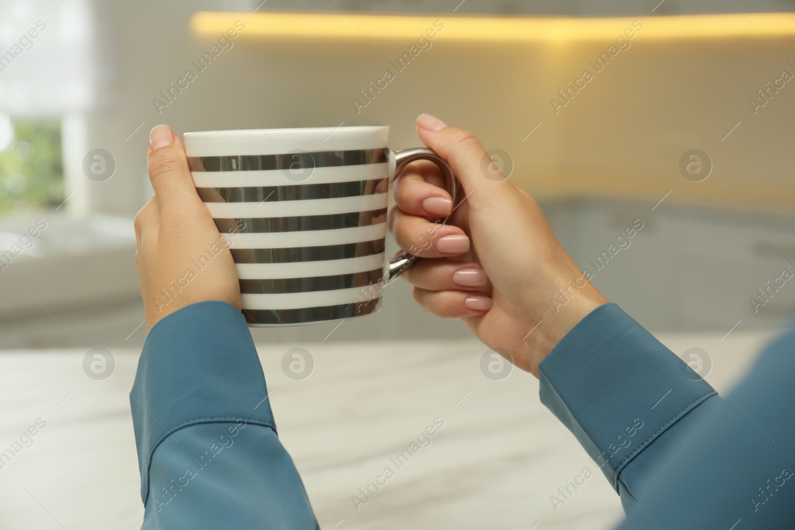 Photo of Woman holding elegant cup in kitchen, closeup