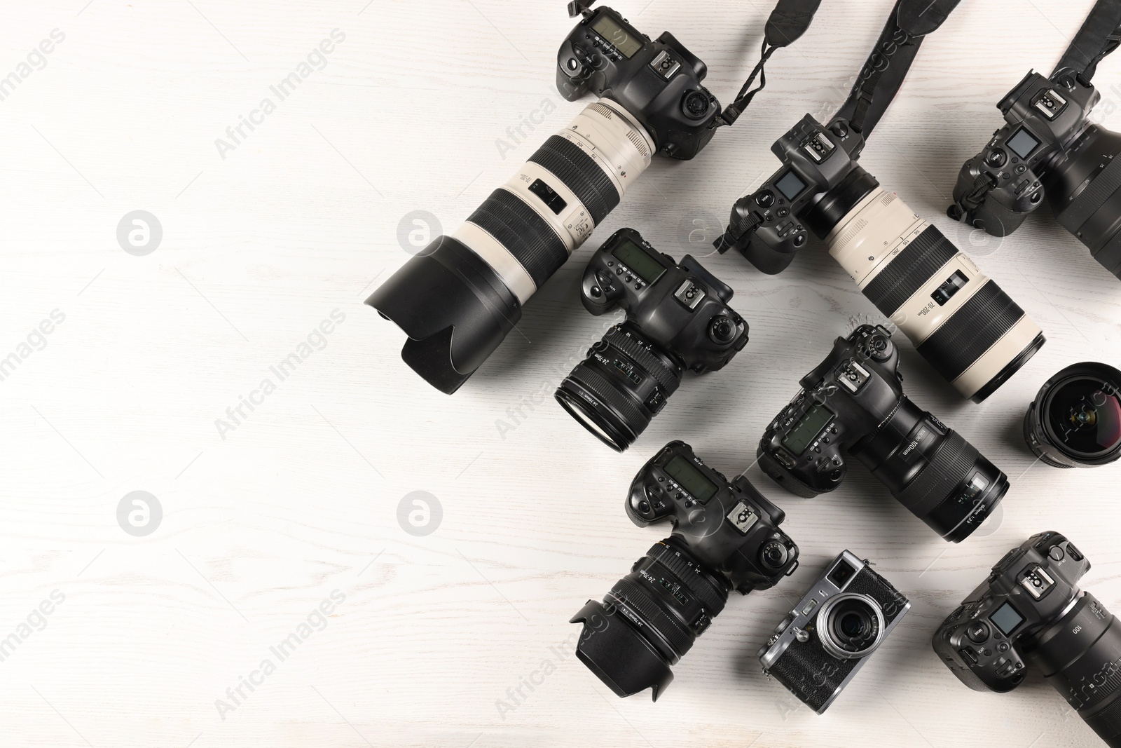 Photo of Modern cameras on white wooden table, flat lay. Space for text