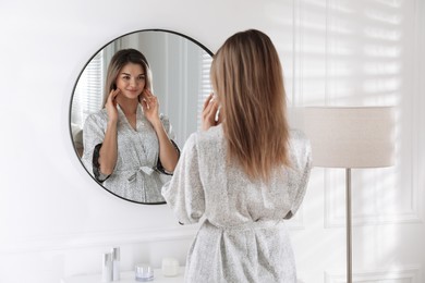 Photo of Beautiful young woman near mirror in room