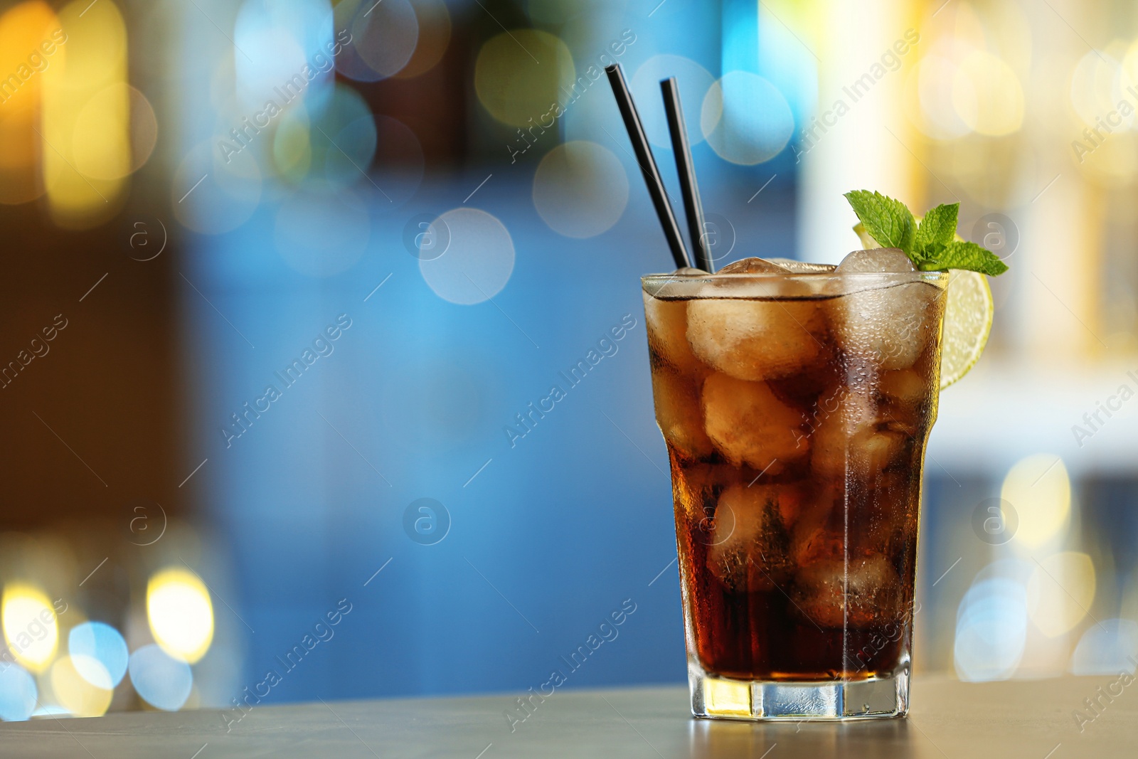 Photo of Glass of fresh alcoholic cocktail with lemon and mint on bar counter, space for text