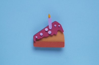 Birthday party. Paper cake with candle on light blue background, top view