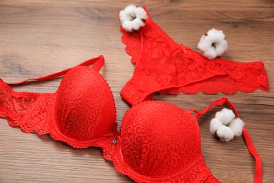 Elegant red women's underwear and cotton flowers on wooden background