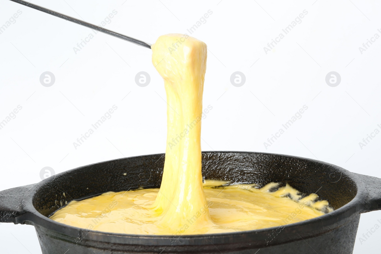 Photo of Dipping piece of ham into fondue pot with tasty melted cheese isolated on white