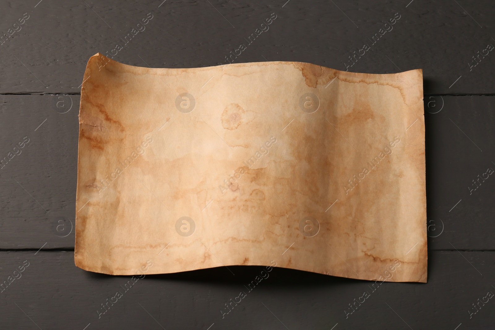 Photo of Sheet of old parchment paper on grey wooden table, above view