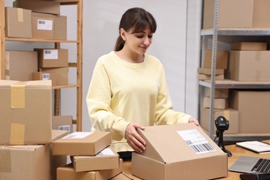 Photo of Post office worker packing parcel at wooden table indoors