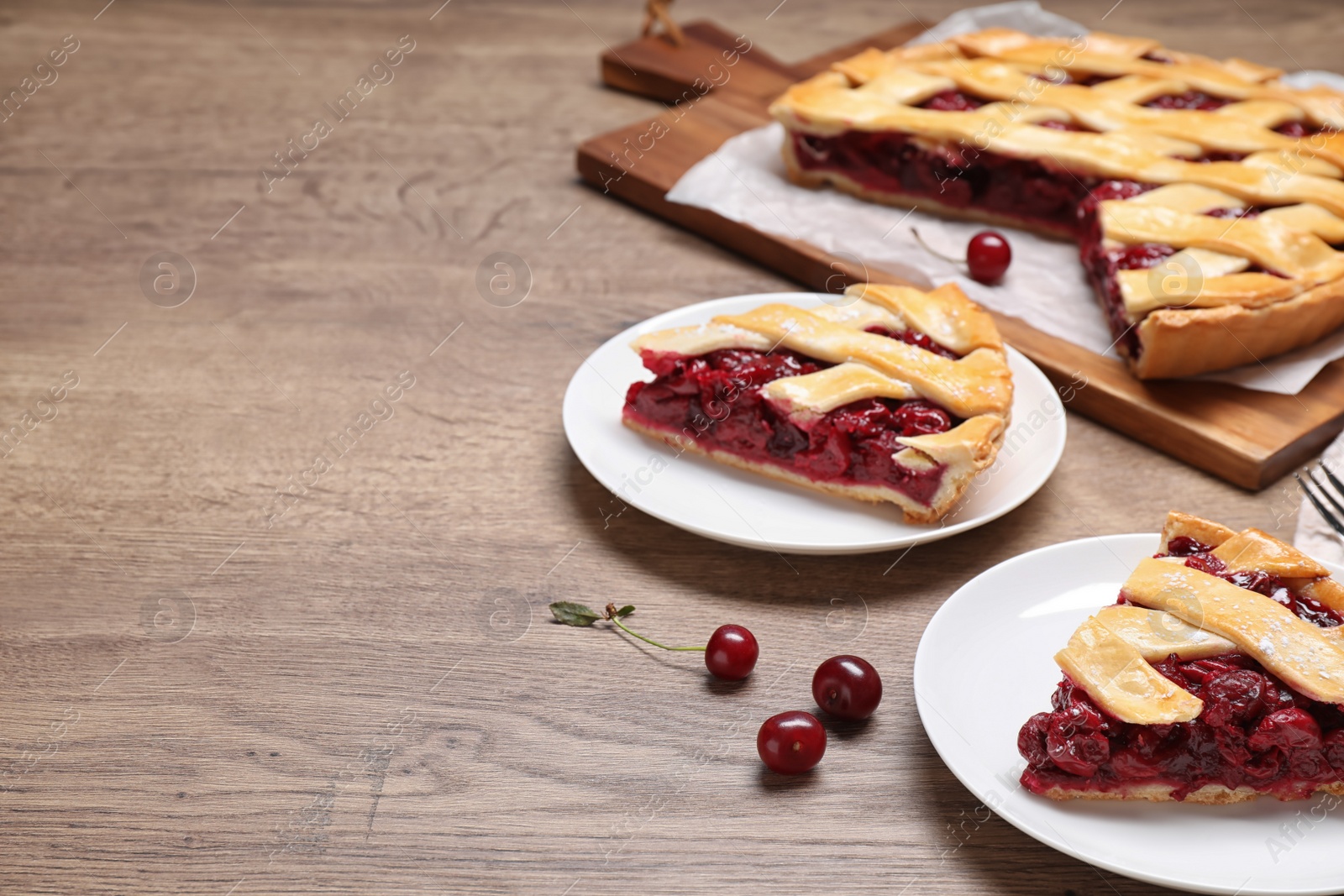 Photo of Slices of delicious fresh cherry pie served on wooden table. Space for text