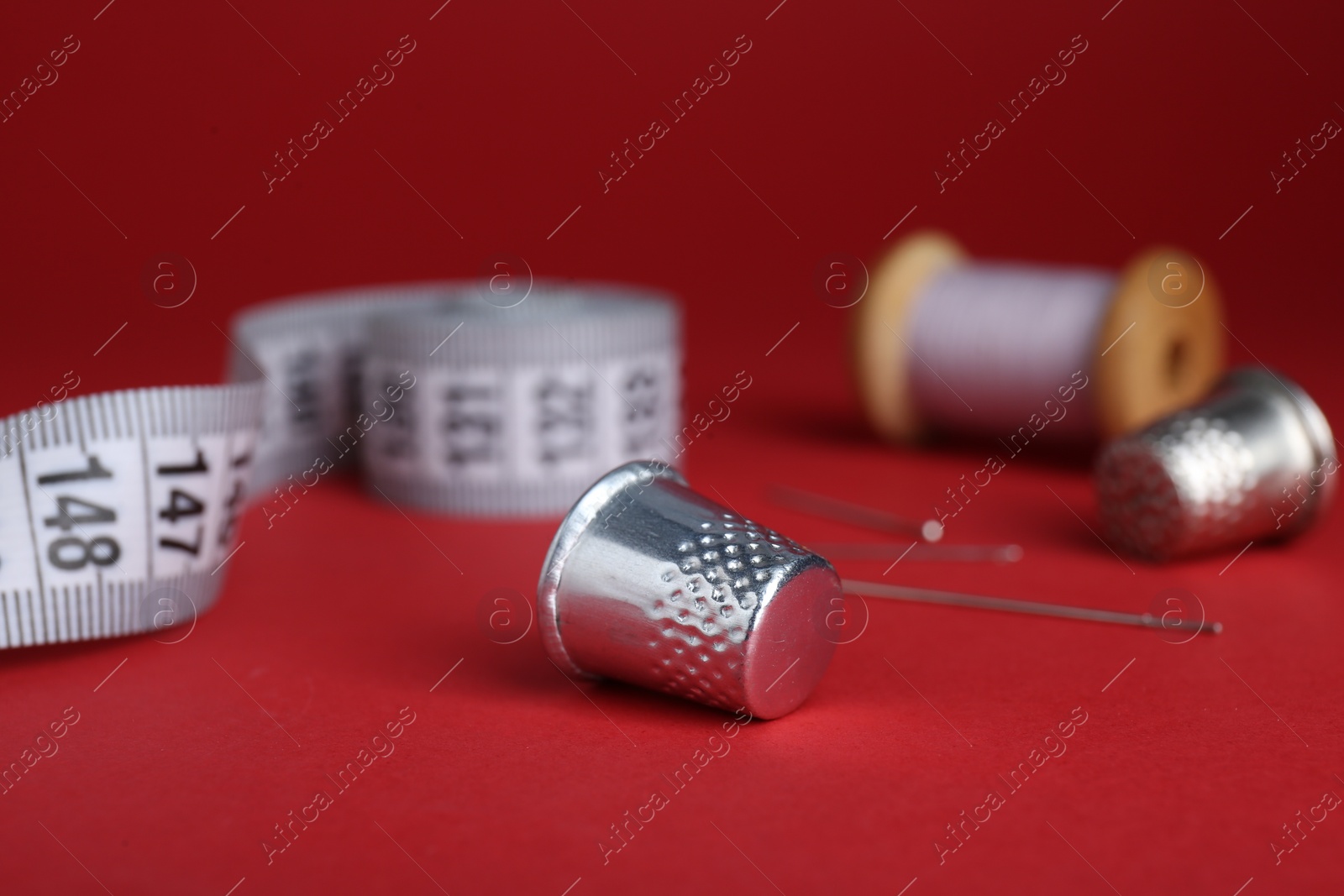 Photo of Silver thimble on red background. Sewing accessories