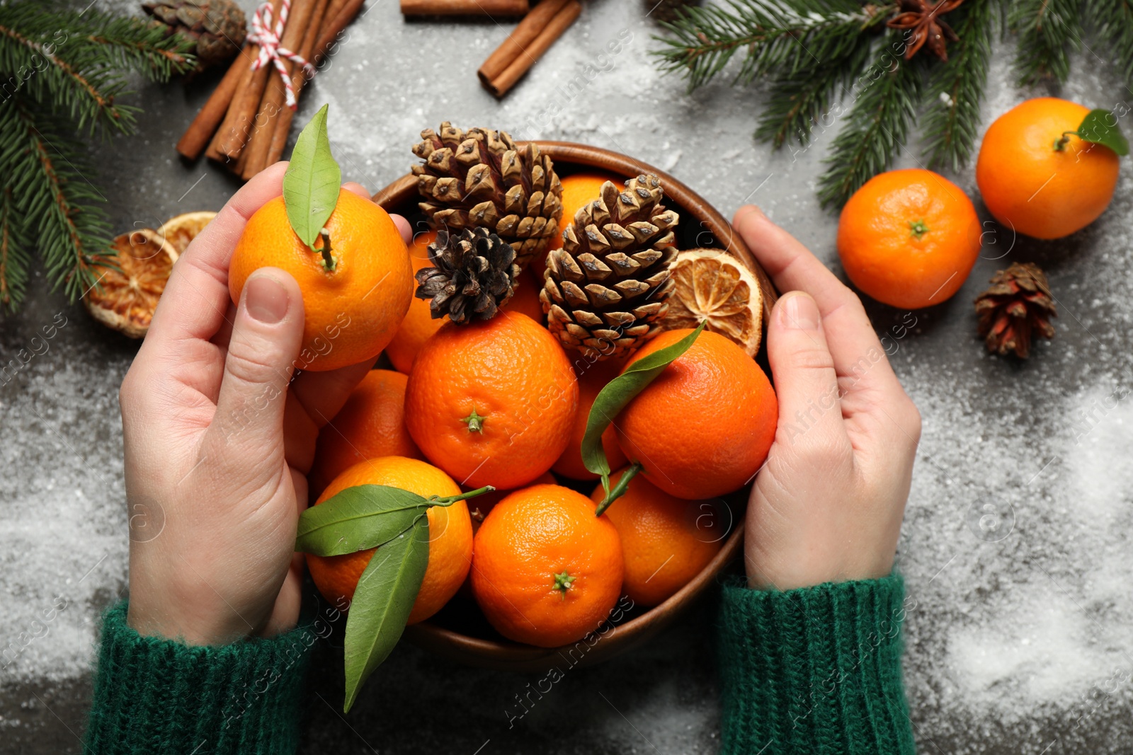 Photo of Woman with fresh tangerines at table, top view. Christmas atmosphere