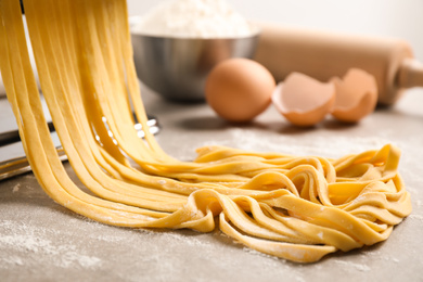 Raw noodles with flour on grey table, closeup. Italian pasta