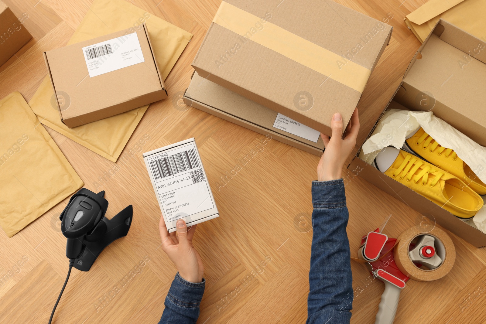 Photo of Woman with parcel at wooden table, top view. Online store