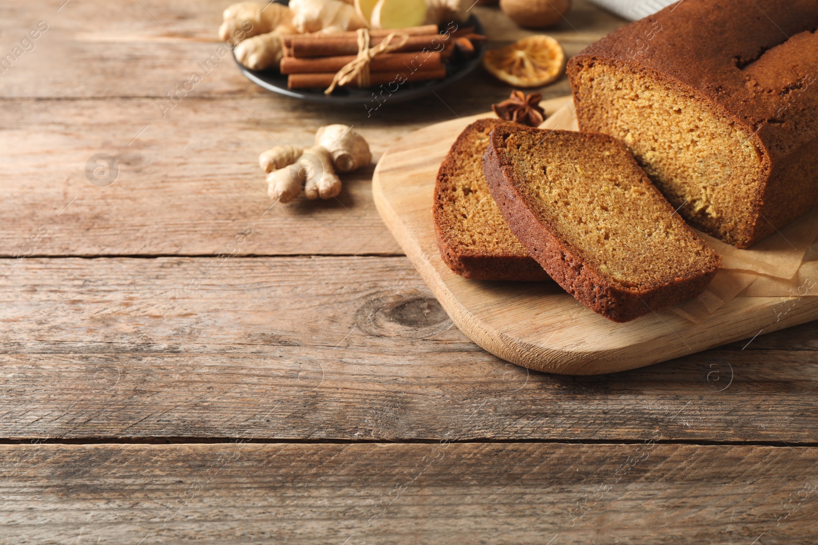 Photo of Fresh sliced gingerbread cake on wooden table, space for text