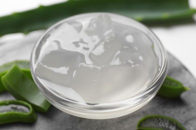 Aloe vera gel and slices of plant on white background, closeup