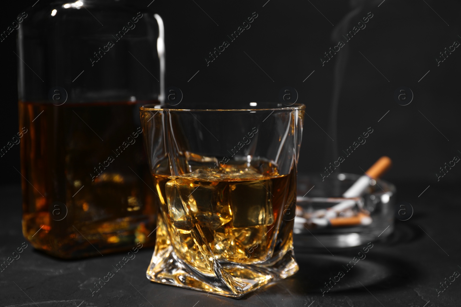 Photo of Alcohol addiction. Whiskey in glass on dark textured table, closeup