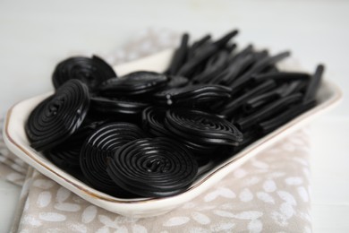 Photo of Tasty black liquorice candies on white table, closeup
