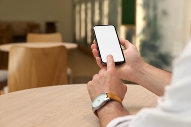 Photo of Man using mobile phone at table indoors, closeup. Space for text