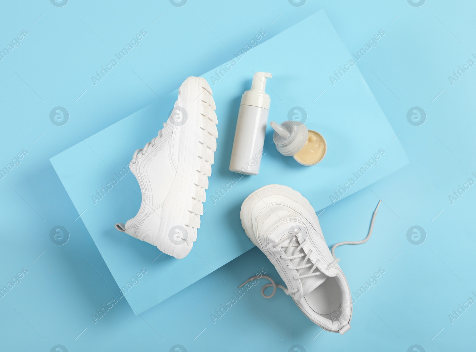 Photo of Stylish footwear and shoe care accessories on light blue background, flat lay