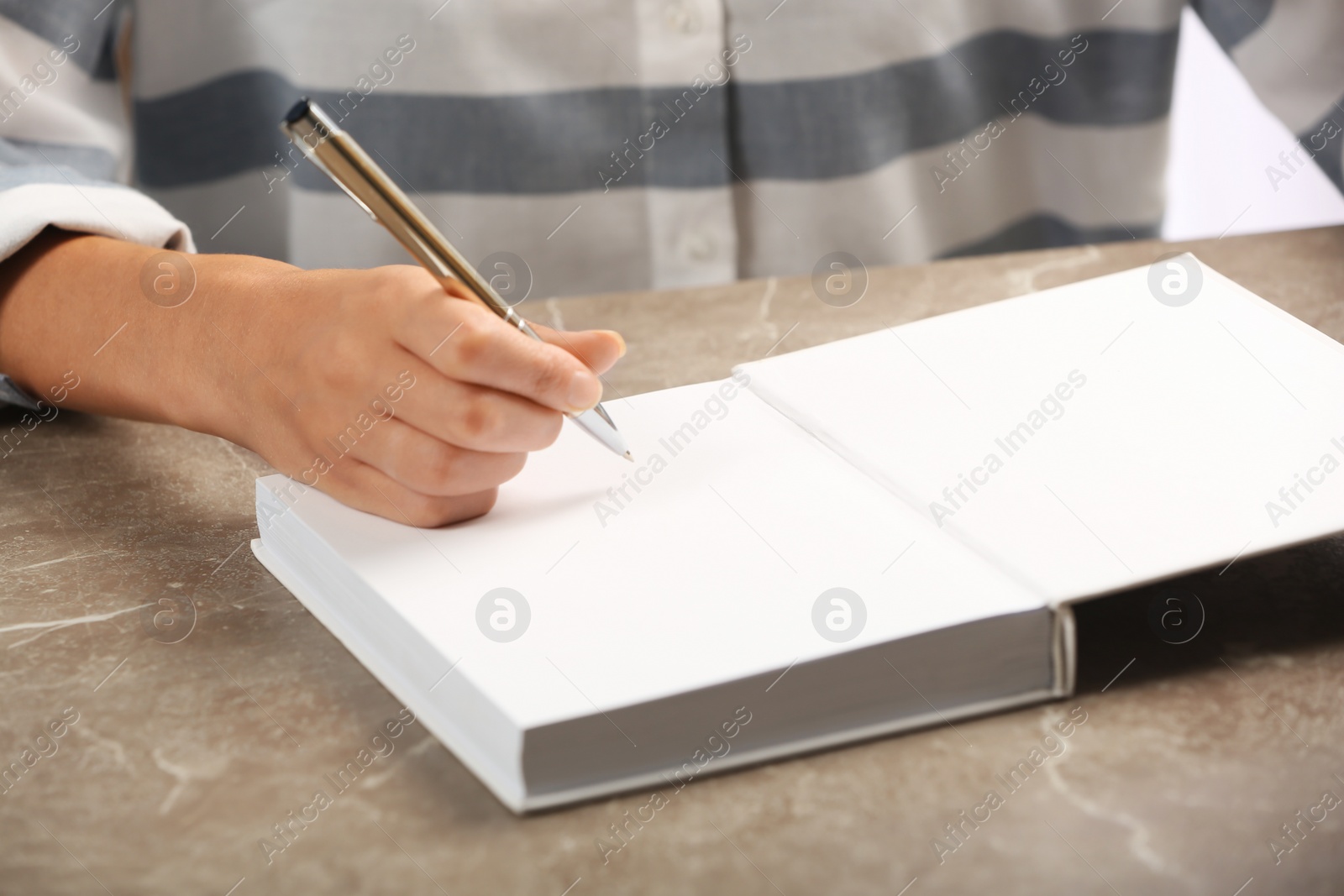 Photo of Writer signing autograph in book at table, closeup