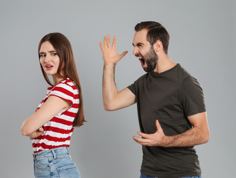 Photo of Man shouting at his girlfriend on grey background. Relationship problems