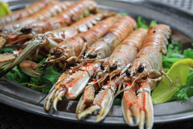 Photo of Plate with tasty boiled crayfish and salad on table, closeup