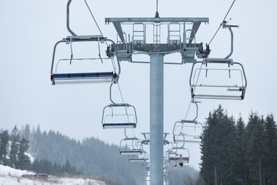 Photo of Chairlift with people at ski resort. Winter vacation