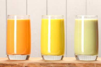 Photo of Board with many different tasty smoothies against white wooden background, closeup