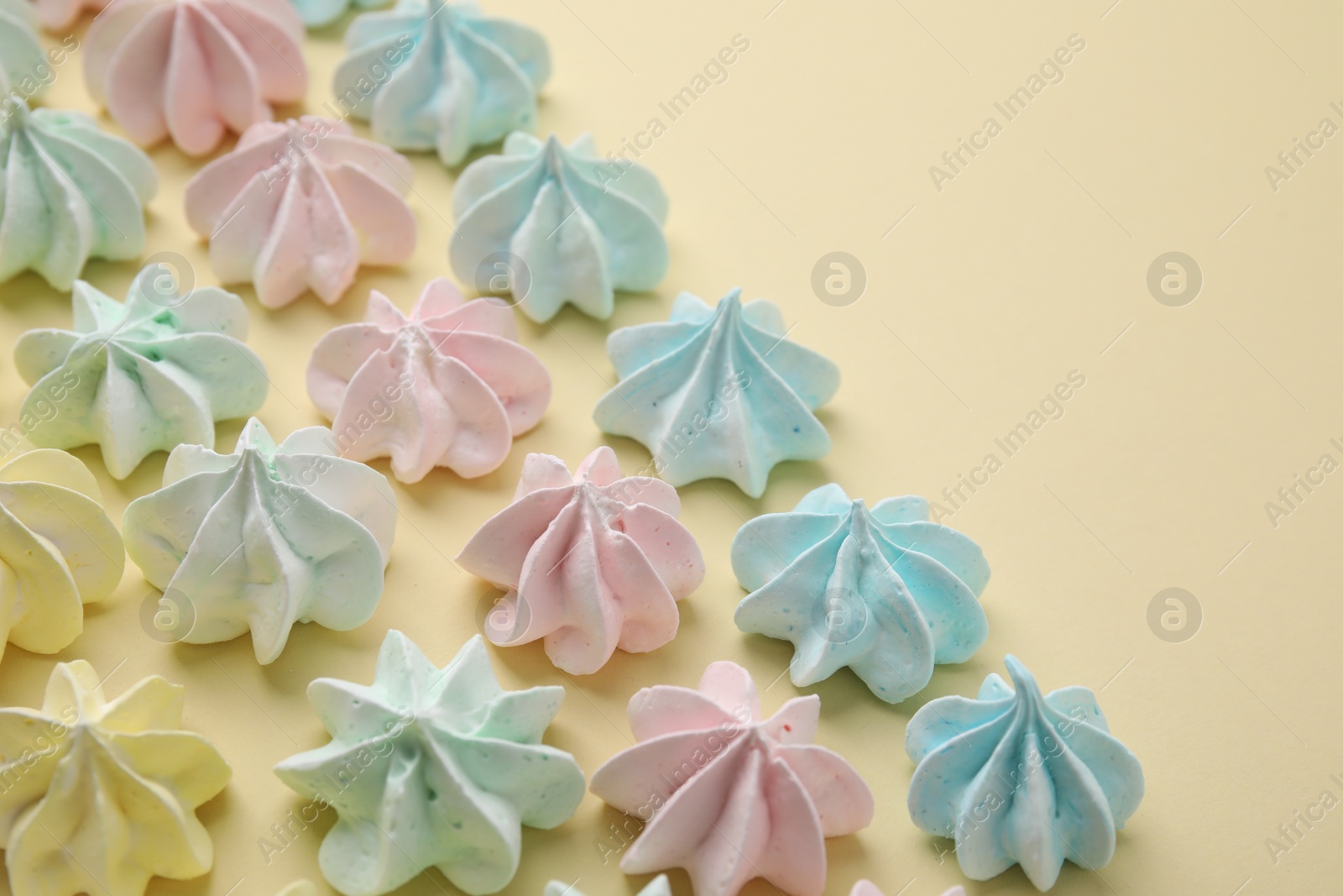 Photo of Delicious meringue cookies on beige background, closeup. Space for text