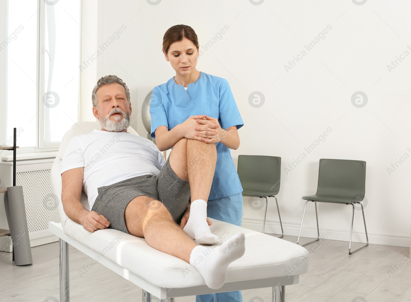 Photo of Physiotherapist working with patient in clinic. Rehabilitation therapy