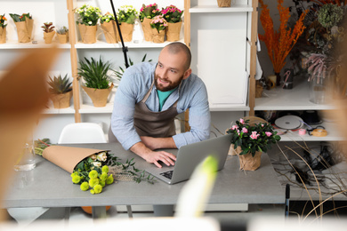Photo of Professional male florist using laptop at workplace