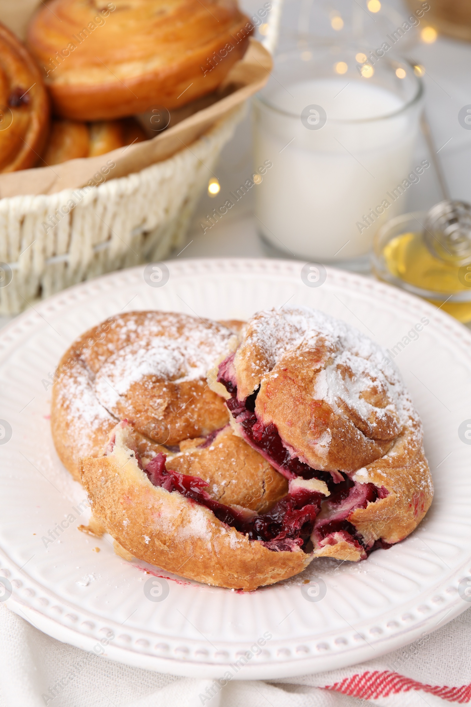 Photo of Delicious bun with sugar powder and berries on table, closeup