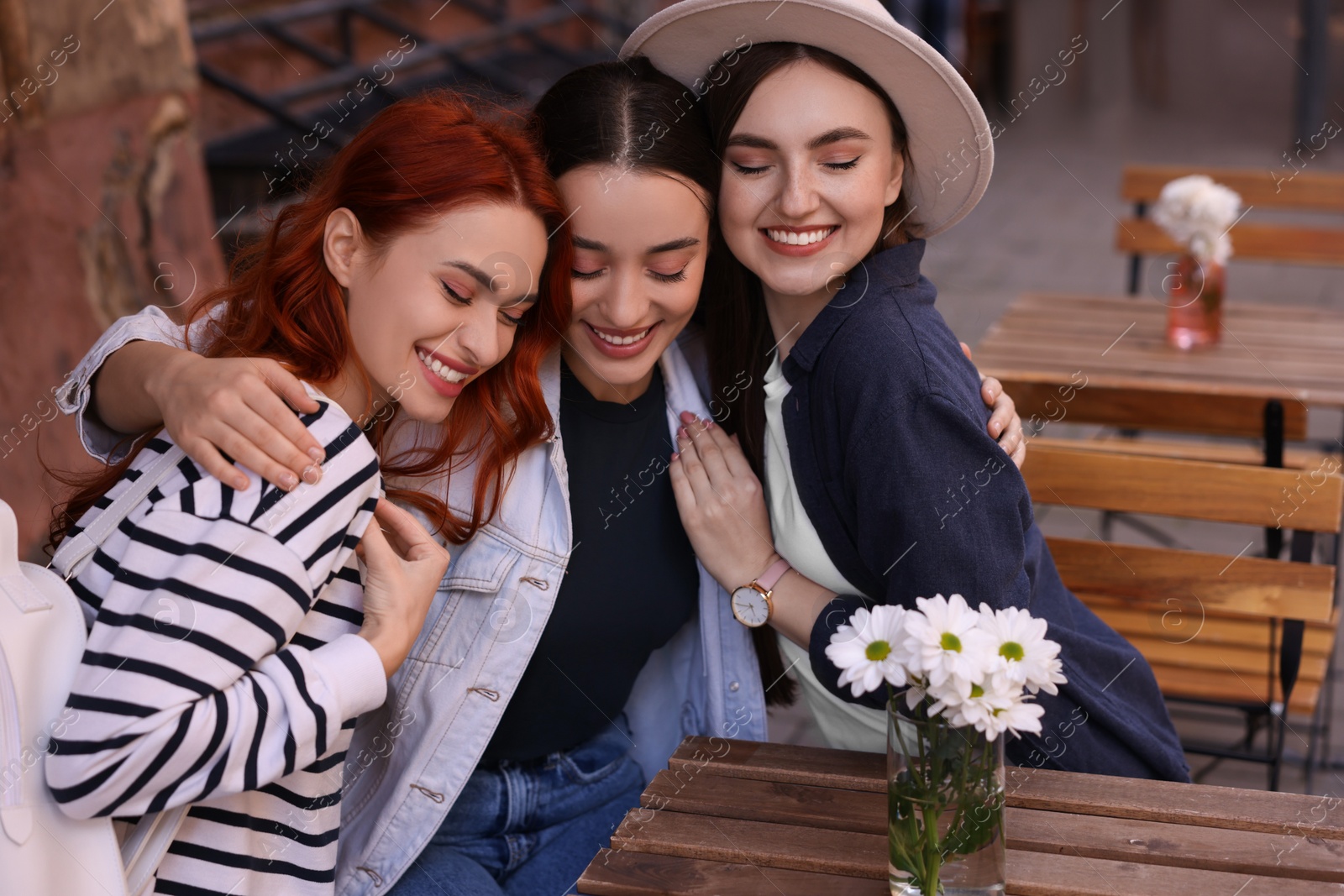 Photo of Happy friends spending time together in outdoor cafe