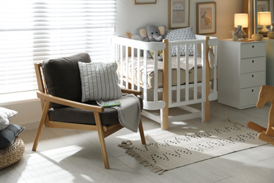 Photo of Baby room interior with crib and armchair. Idea for design