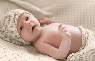 Adorable newborn baby in hat lying on bed