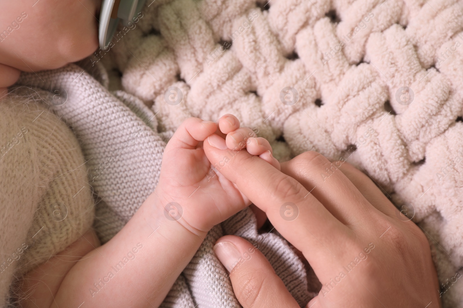 Photo of Mother and her newborn baby on beige crocheted plaid, top view