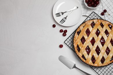 Flat lay composition with tasty cherry pie on light grey table. Space for text