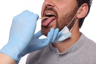 Doctor examining man`s oral cavity with tongue depressor on white background, closeup