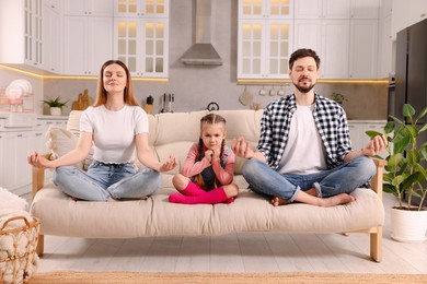 Photo of Parents meditating while their daughter getting bored at home. Harmony and zen