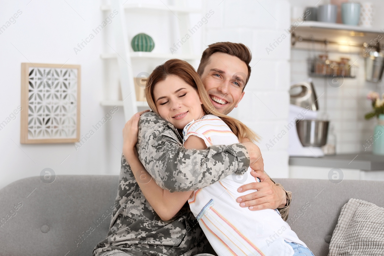 Photo of Young man in military uniform with his wife on sofa at home