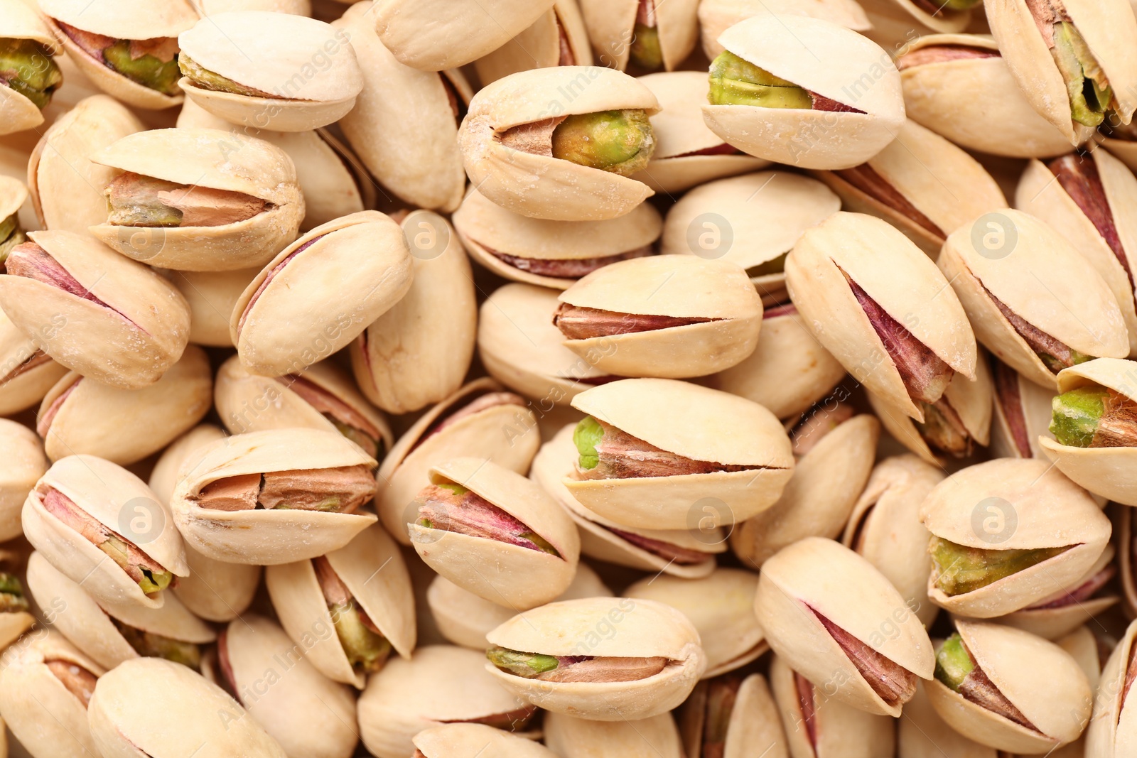 Photo of Tasty unpeeled pistachios as background, top view