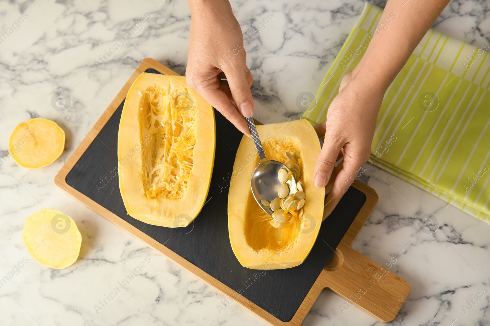 Photo of Woman removing seeds from spaghetti squash on table, top view