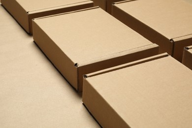 Many closed cardboard boxes on light brown background, closeup