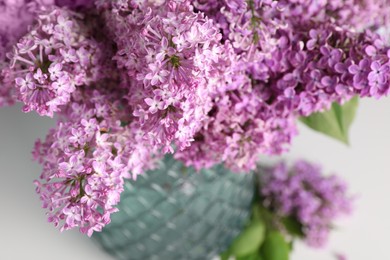 Beautiful lilac flowers in vase on light background, closeup