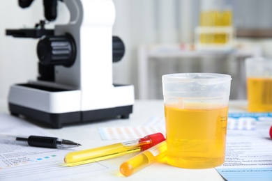 Photo of Laboratory ware with urine sample for analysis on white table indoors