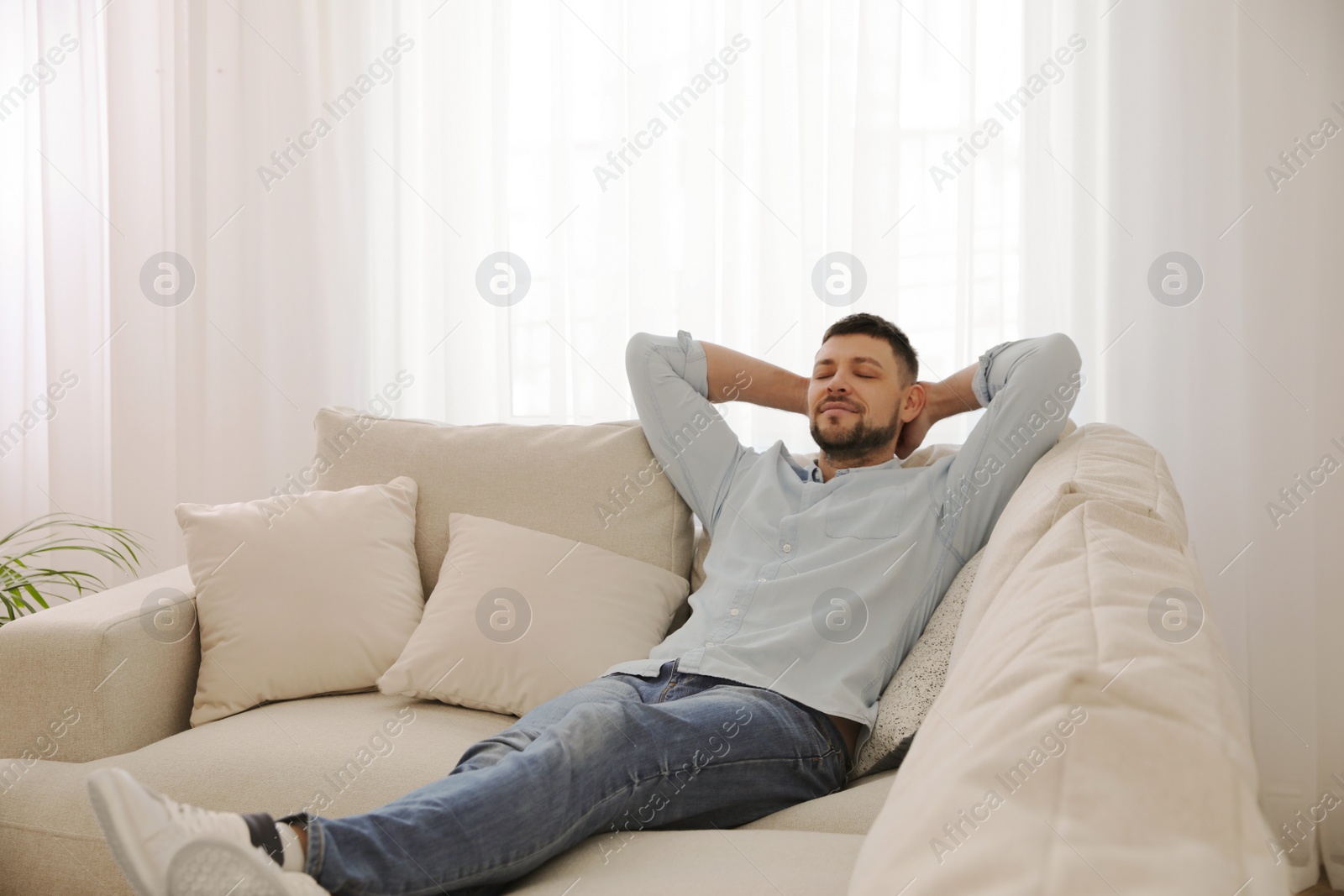 Photo of Man resting on comfortable sofa in living room