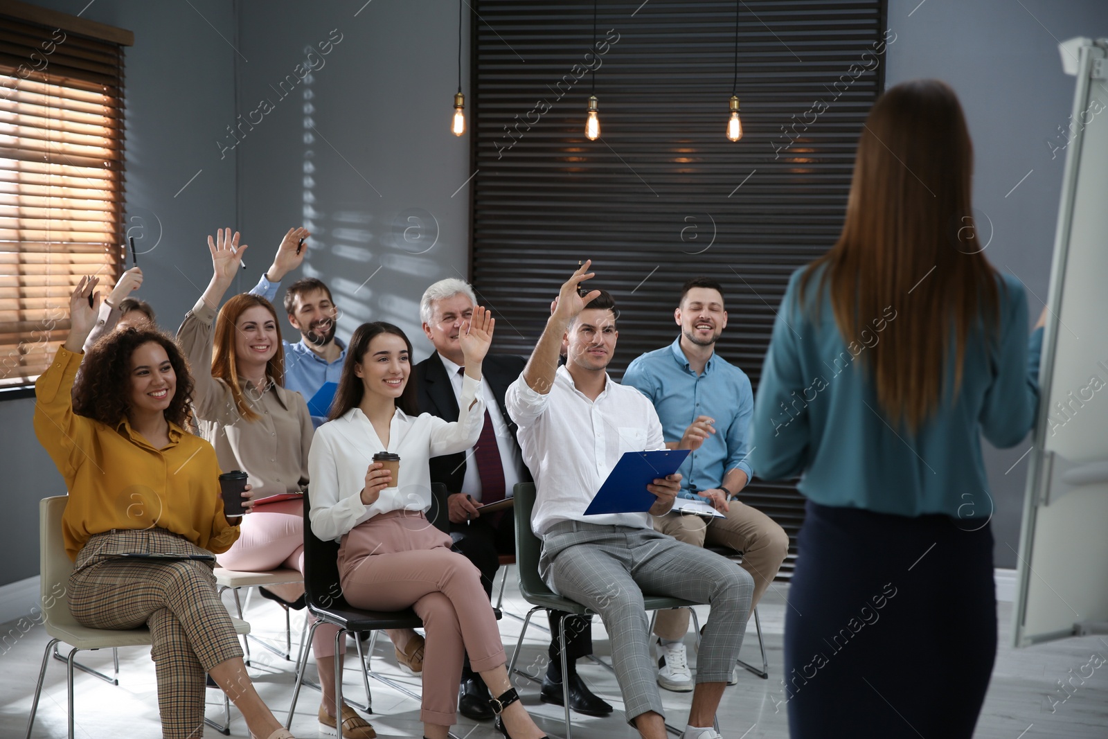 Photo of People raising hands to ask questions at seminar in office