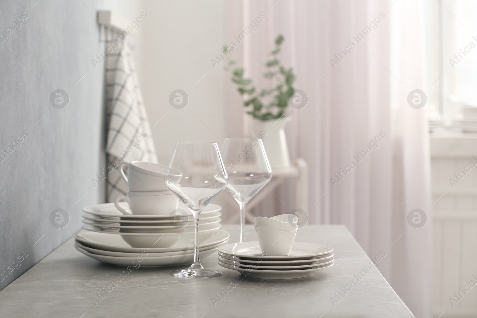 Photo of Set of clean dishware and wineglasses on grey table indoors