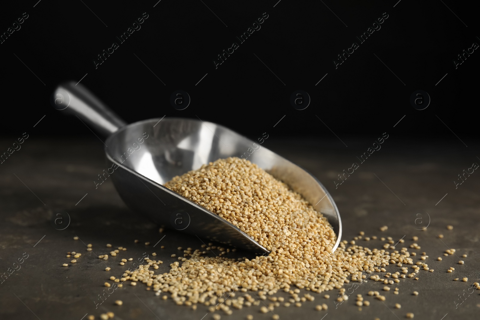 Photo of Metal scoop with white quinoa on grey table. Space for text