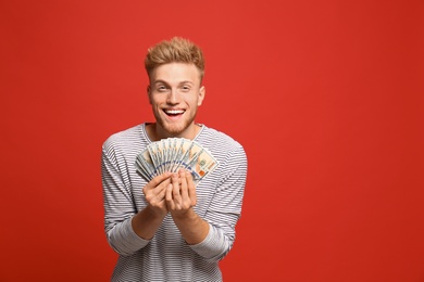 Portrait of happy lottery winner with money on red background